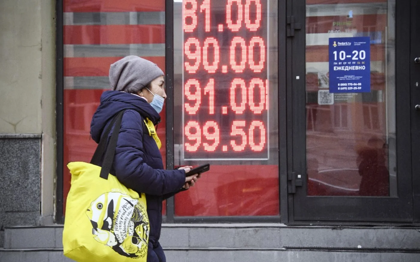 Une femme passe devant un bureau de change à Moscou, le 24 février (AFP)