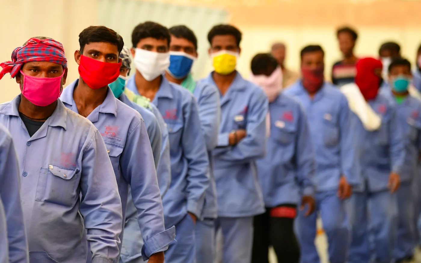 Des travailleurs migrants font la queue pour monter dans un bus les transportant vers leur lieu de travail, à Dubaï, le 2 avril 2020 (AFP)
