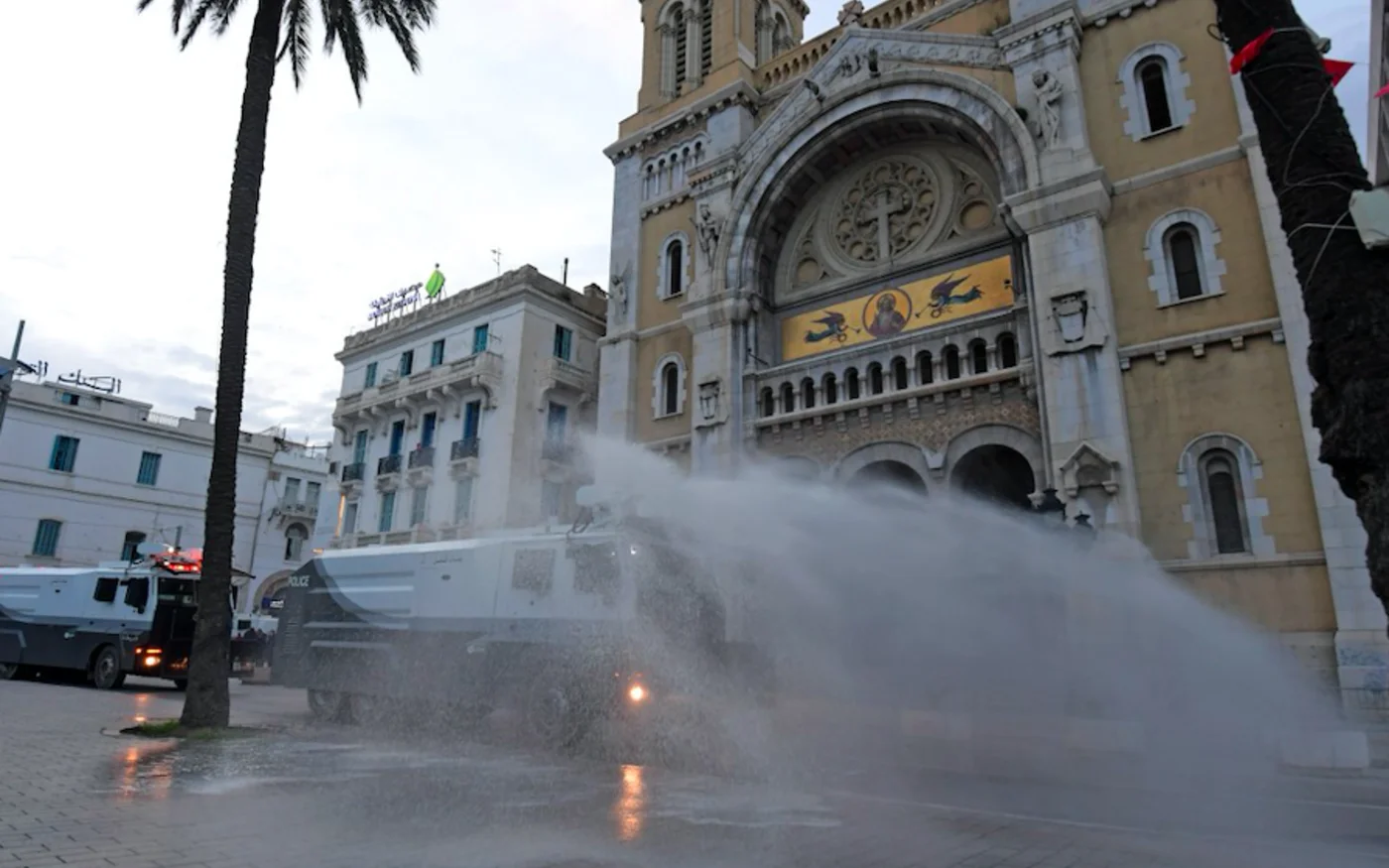 Des camions de police tunisiens pulvérisent du désinfectant à l’extérieur de la cathédrale Saint-Vincent de Paul dans le centre de la capitale Tunis, le 1er avril 2020 (AFP)