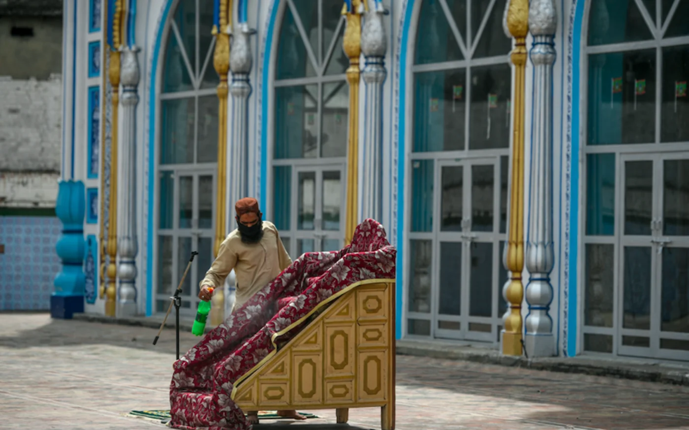 Un fidèle désinfecte une chaire, également connue sous le nom de minbar, dans une mosquée au Pakistan, le 3 avril 2020 (AFP)