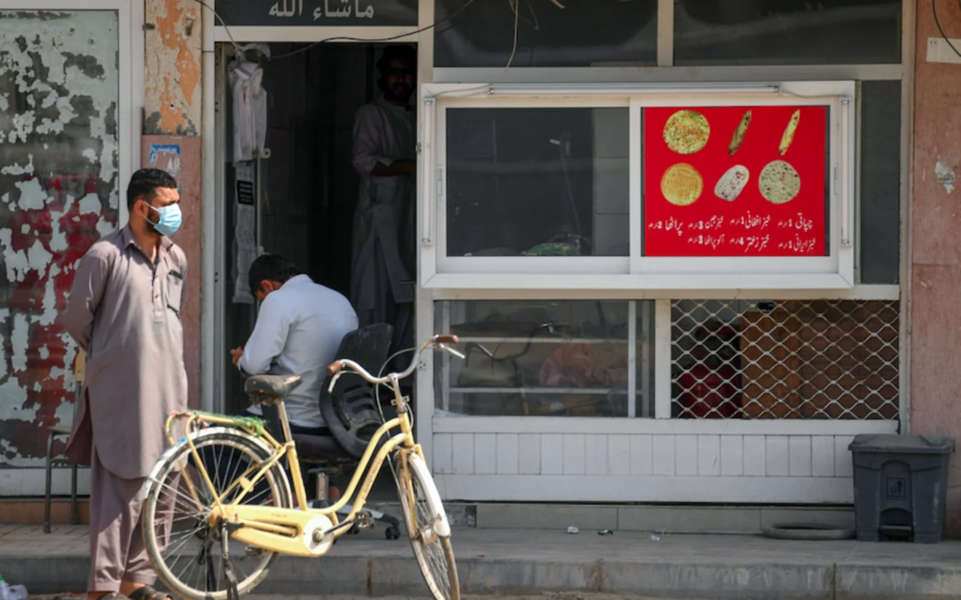 Un travailleur portant un masque attend devant une boulangerie à Sharjah, dans les Émirats arabes unis, le 26 mars 2020 (AFP)