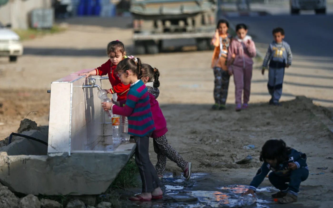 Des enfants palestiniens remplissent des bouteilles en plastique avec de l'eau dans un camp de réfugiés à Khan Yunis, dans le sud de la bande de Gaza, le 11 avril 2020 (AFP)