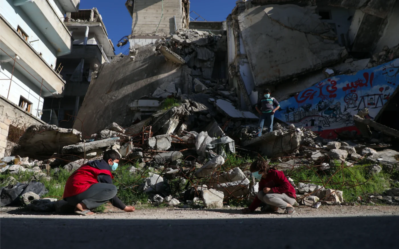 Des enfants jouent devant un bâtiment, détruit par les frappes aériennes des forces pro-régime, dans la ville d'Ariha, dans la campagne sud de la province d'Idlib, le 11 avril 2020 (AFP)