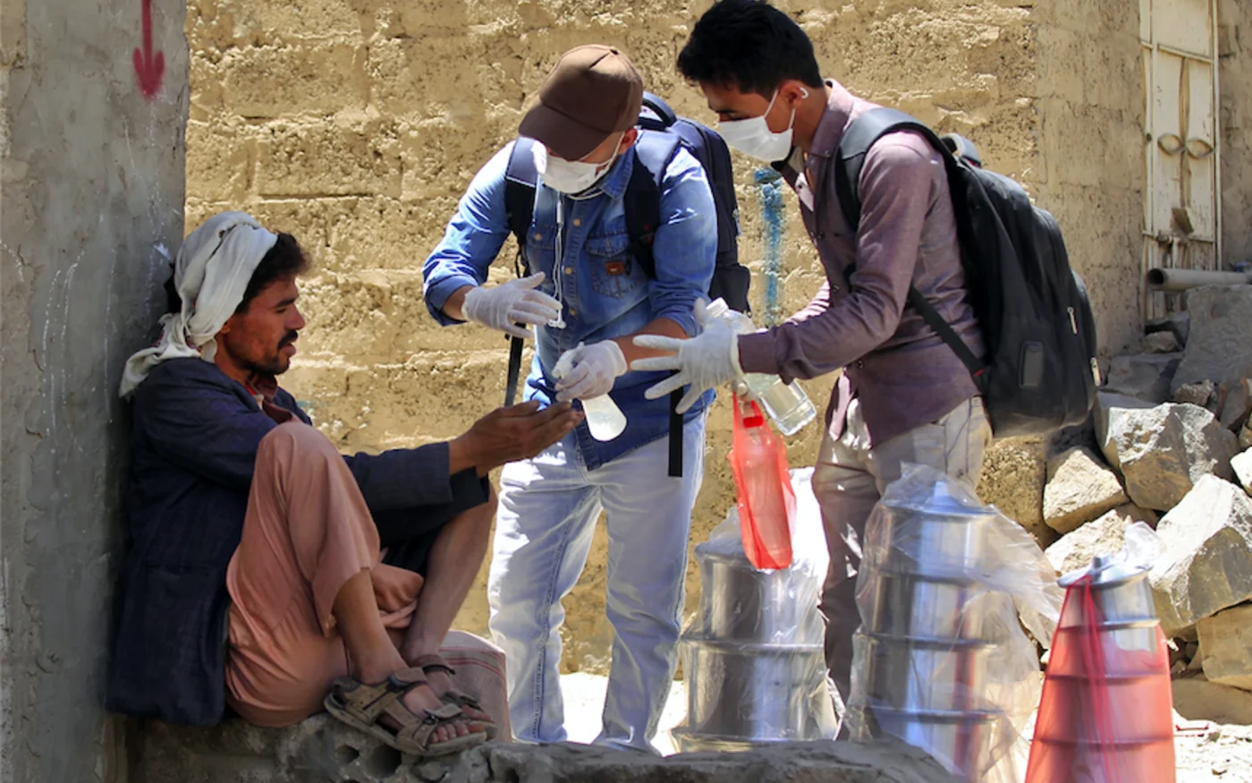 Des volontaires yéménites pulvérisent du désinfectant sur les mains d'un homme, dans l'un des quartiers pauvres de Sanaa, le 30 mars 2020 (AFP)