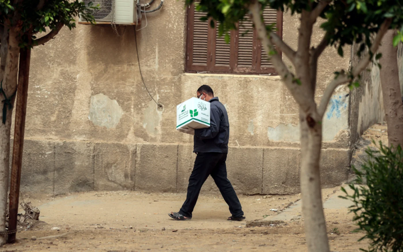 Un Égyptien transporte une boîte contenant des denrées alimentaires distribués par l'ONG Egyptian Food Bank, au Caire, le 5 avril 2020 (AFP)