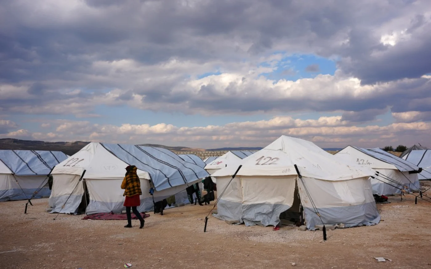 Un Syrien, déplacé à la suite du tremblement de terre meurtrier qui a frappé la Turquie et la Syrie, passe devant des tentes dans un camp temporaire, dans la campagne de Jandairis, dans le nord-ouest de la Syrie, le 11 février 2023 (AFP/Rami al-Sayed)