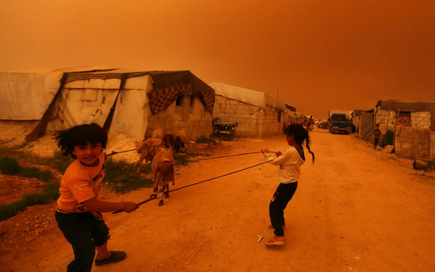 Des enfants déplacés passent devant des tentes lors d’une tempête de sable à la périphérie de la ville de Dana, dans la province d’Idleb, au nord-ouest, près de la frontière turco-syrienne, le 2 juin 2022 (AFP/Aaref Watad)