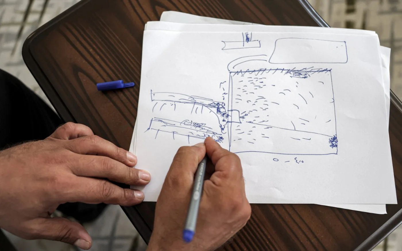 Moatassem Abdel Sater, ancien détenu de 42 ans de la prison de Sednaya, dessine un croquis rudimentaire du plan de la prison, le 10 août 2022. (AFP/Omar Haj Kaddour)