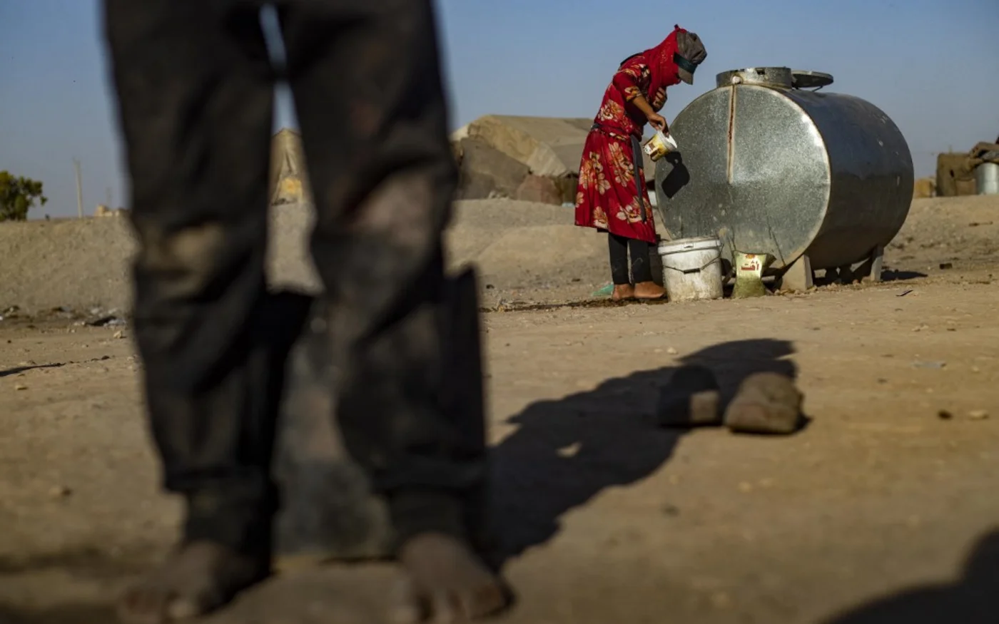 Une Syrienne remplit un seau d’eau dans le camp de Sahlah al-Banat dans la campagne de Raqqa, dans le nord de la Syrie, le 19 septembre 2022 (AFP/Delil Souleiman)