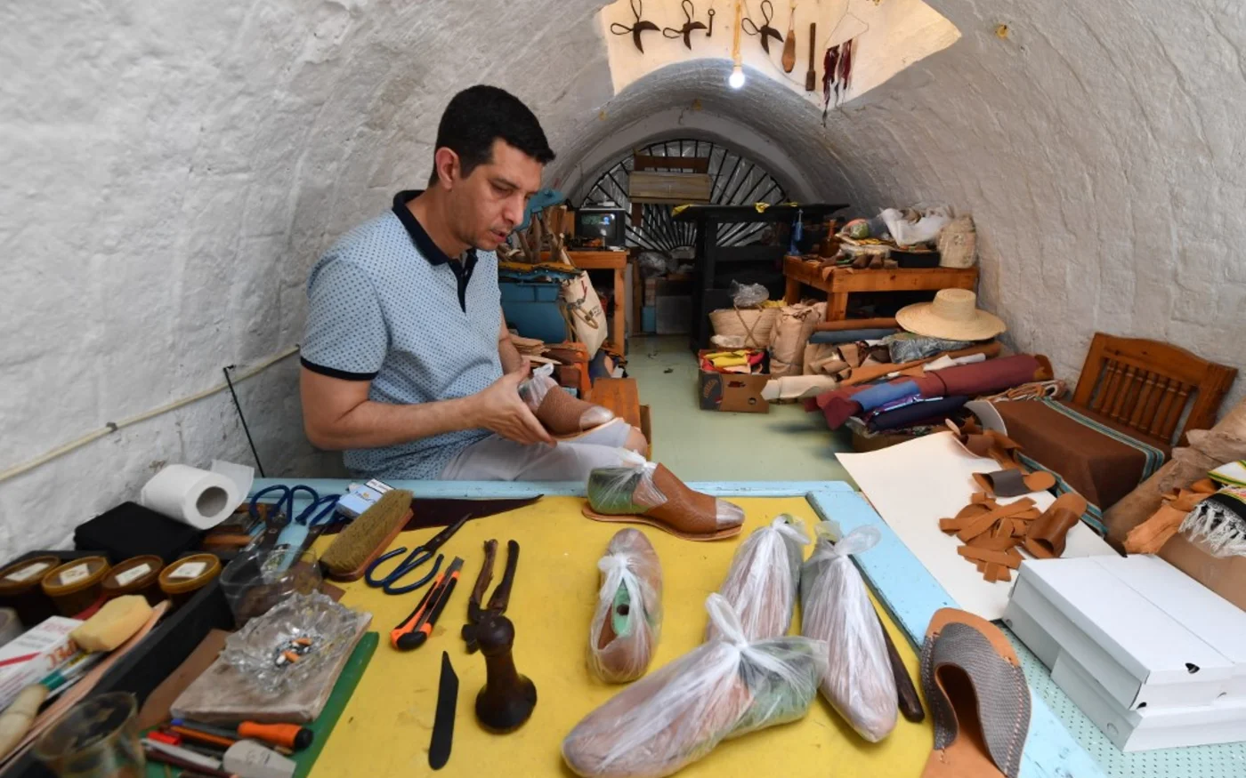 L’artisan tunisien Souhail Fitouri fabrique des chaussons traditionnels en cuir, «&nbsp;balgha&nbsp;», dans son atelier de l’ancienne médina de Tunis, le 21 mai 2022 (AFP/Fethi Belaid)