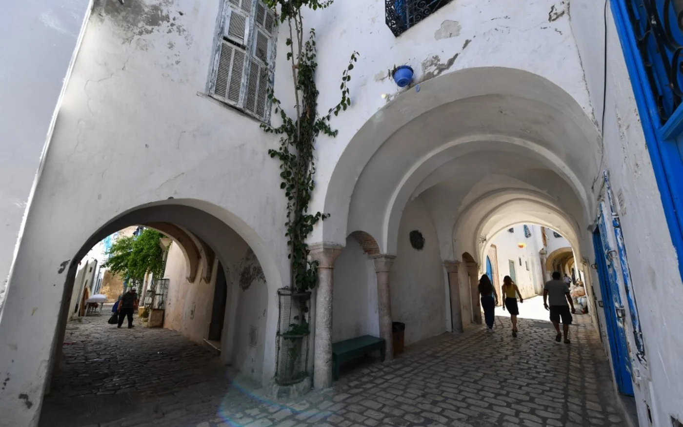 Des Tunisiens marchent dans les rues étroites de l’ancienne médina de Tunis, le 21 mai 2022 (AFP/Fethi Belaid)
