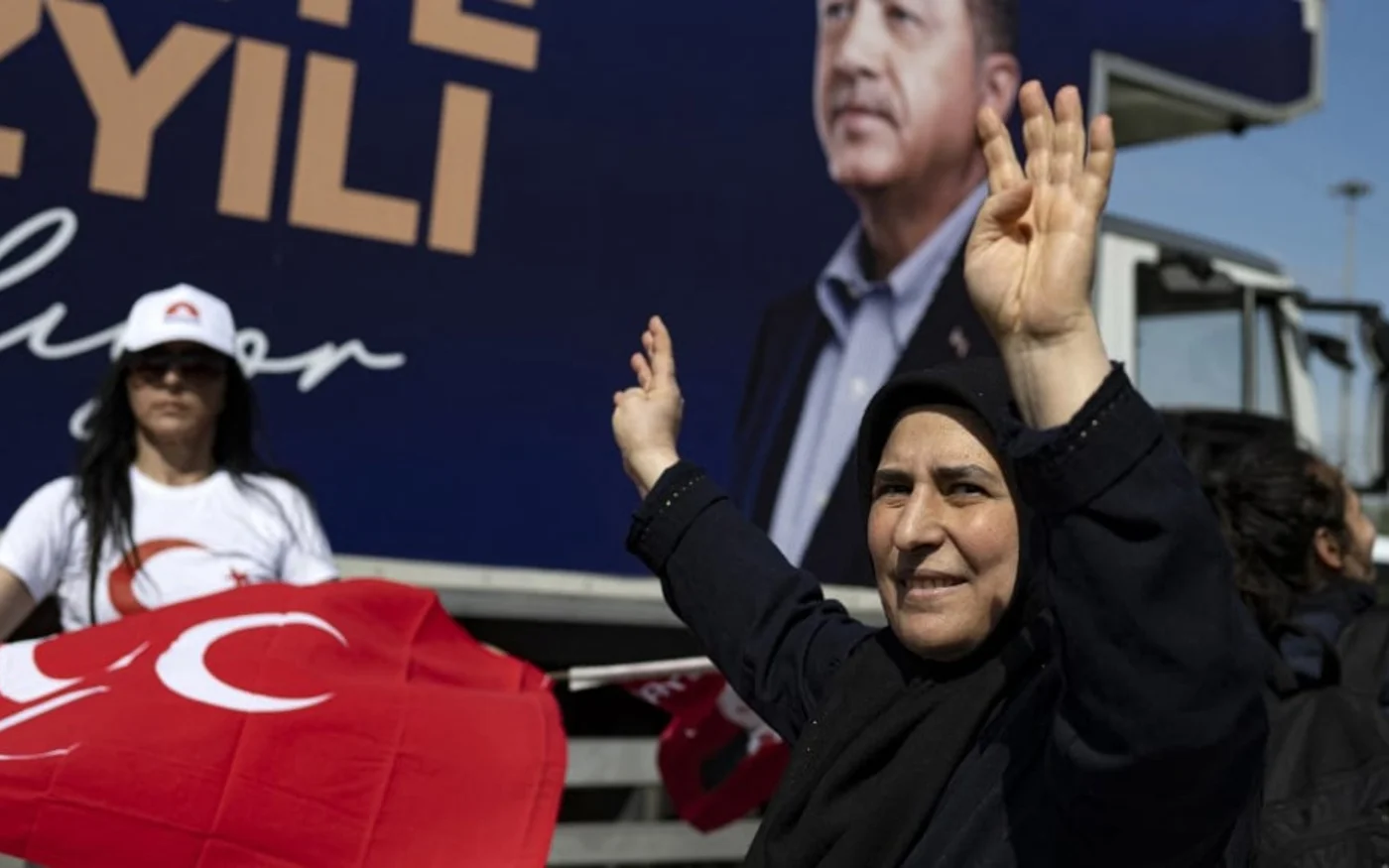 Une femme devant un camion de campagne orné du portrait du président Erdoğan, à Istanbul, le 22 mai 2023 (AFP)