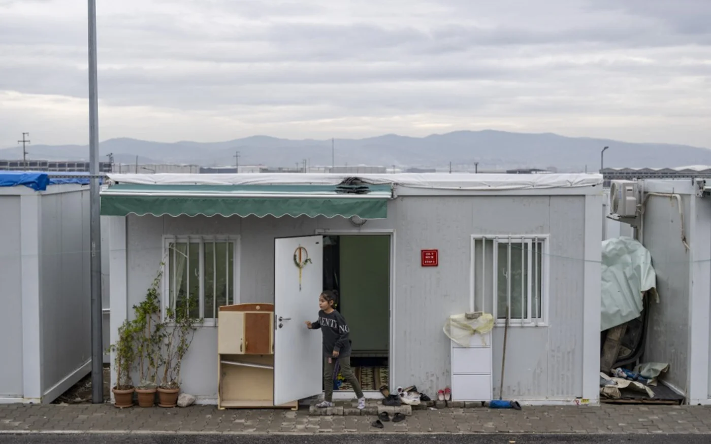 Une jeune fille ferme la porte d'une maison-conteneur à Kahramanmaraş, le 18 janvier 2024 (AFP/Yasin Akgül)