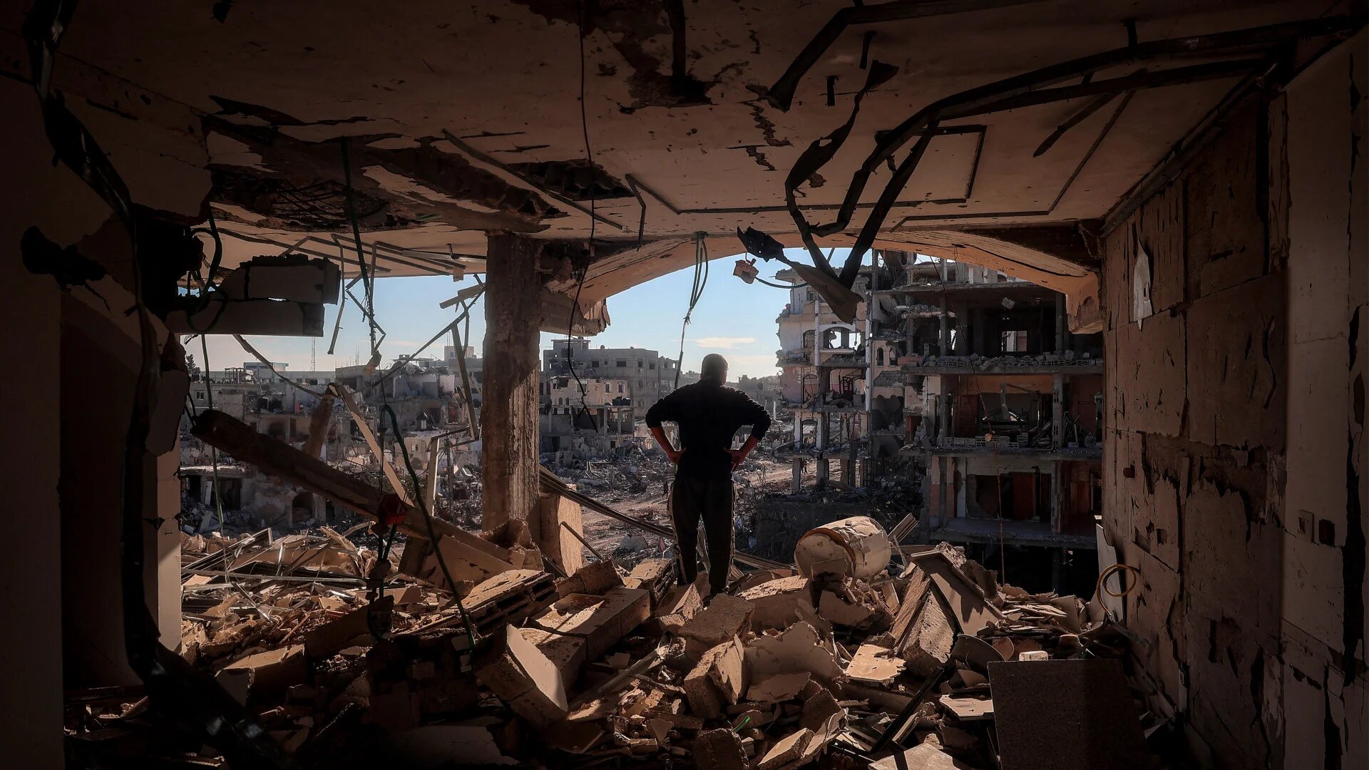 A man stands on the upper floor of a heavily damaged building in Rafah, southern Gaza Strip, on 21 January 2025, as residents return home following a ceasefire deal between Israel and Hamas (Eyad Baba/AFP)