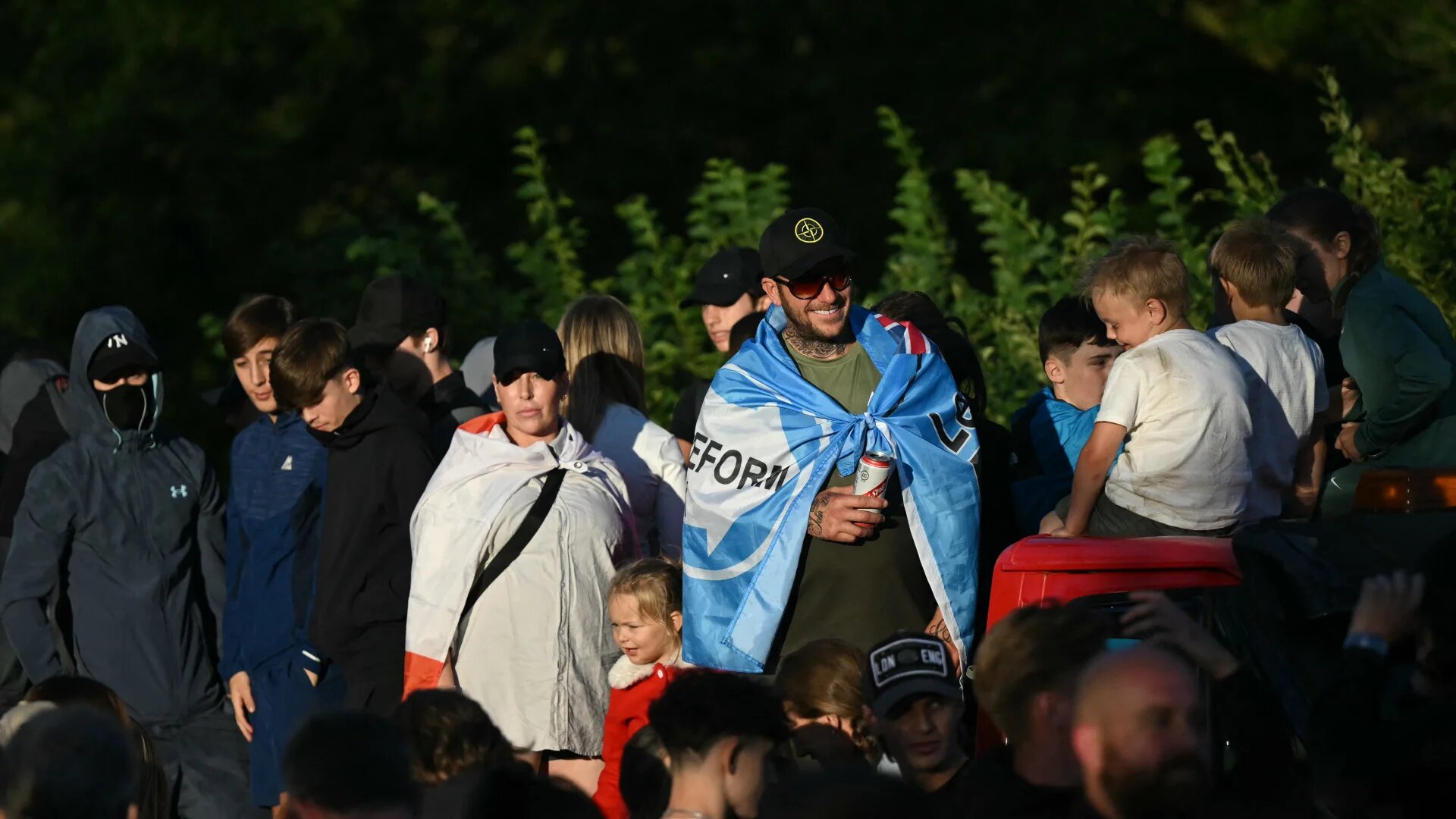 A man wearing a Reform UK flag attends an anti-migrant protest outside The Bell Hotel, believed to be housing asylum seekers, in Epping, northeast of London, on 20 July 2025 (Justin Tallis/AFP)