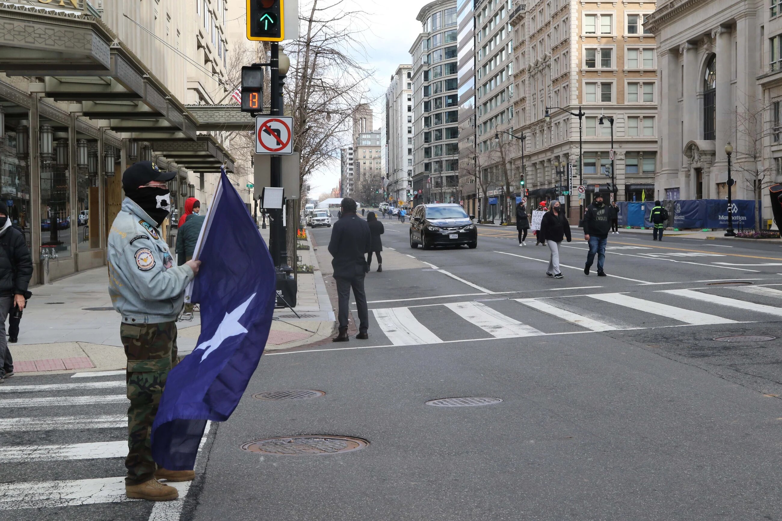 A man stands near a military checkpoint holding a Confederate-era Bonnie Flag