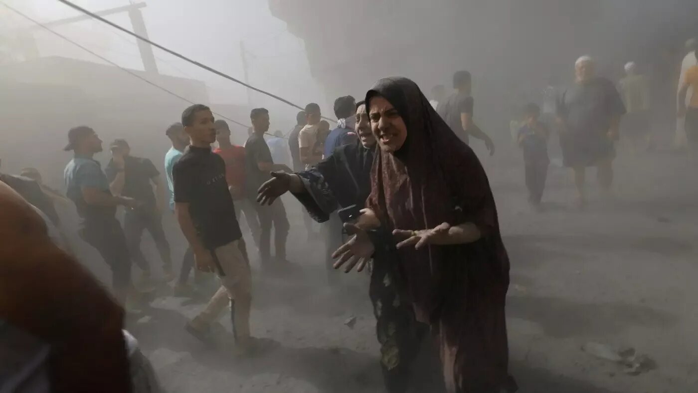 Des Palestiniens passent devant les bâtiments détruits par les bombardements israéliens sur al-Zahra, à la périphérie de la ville de Gaza (AP)