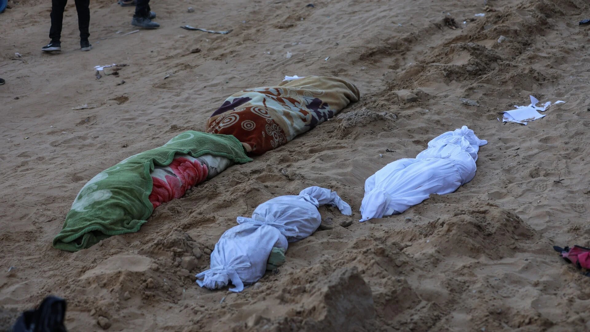 Dead Palestinians, some covered in dirty blankets, lay scattered on the ground around the charred hulk of the hospital building, many of whose outer walls were missing (MEE/Mohammed al-Hajjar)