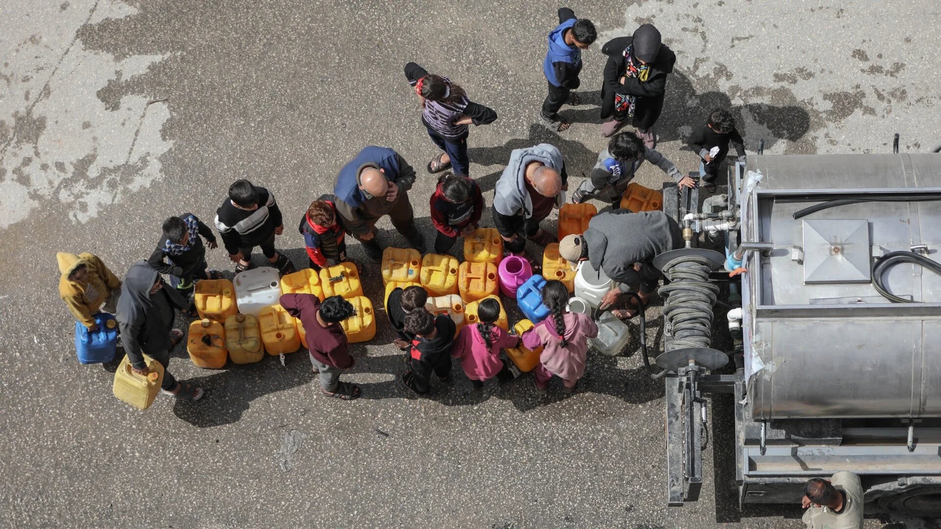 Palestinians queue up near a truck distributing drinkable water as they face the threat of hunger and thirst in Gaza City. According to the UN, more than 96 percent of Gaza's water supply is 'unfit for human consumption' (MEE/Mohammed al-Hajjar)