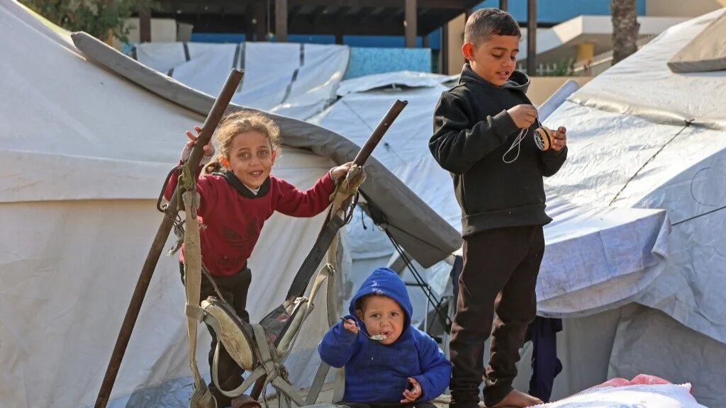 Palestinian children sit outside their makeshift tents in Gaza City on January 11, 2025