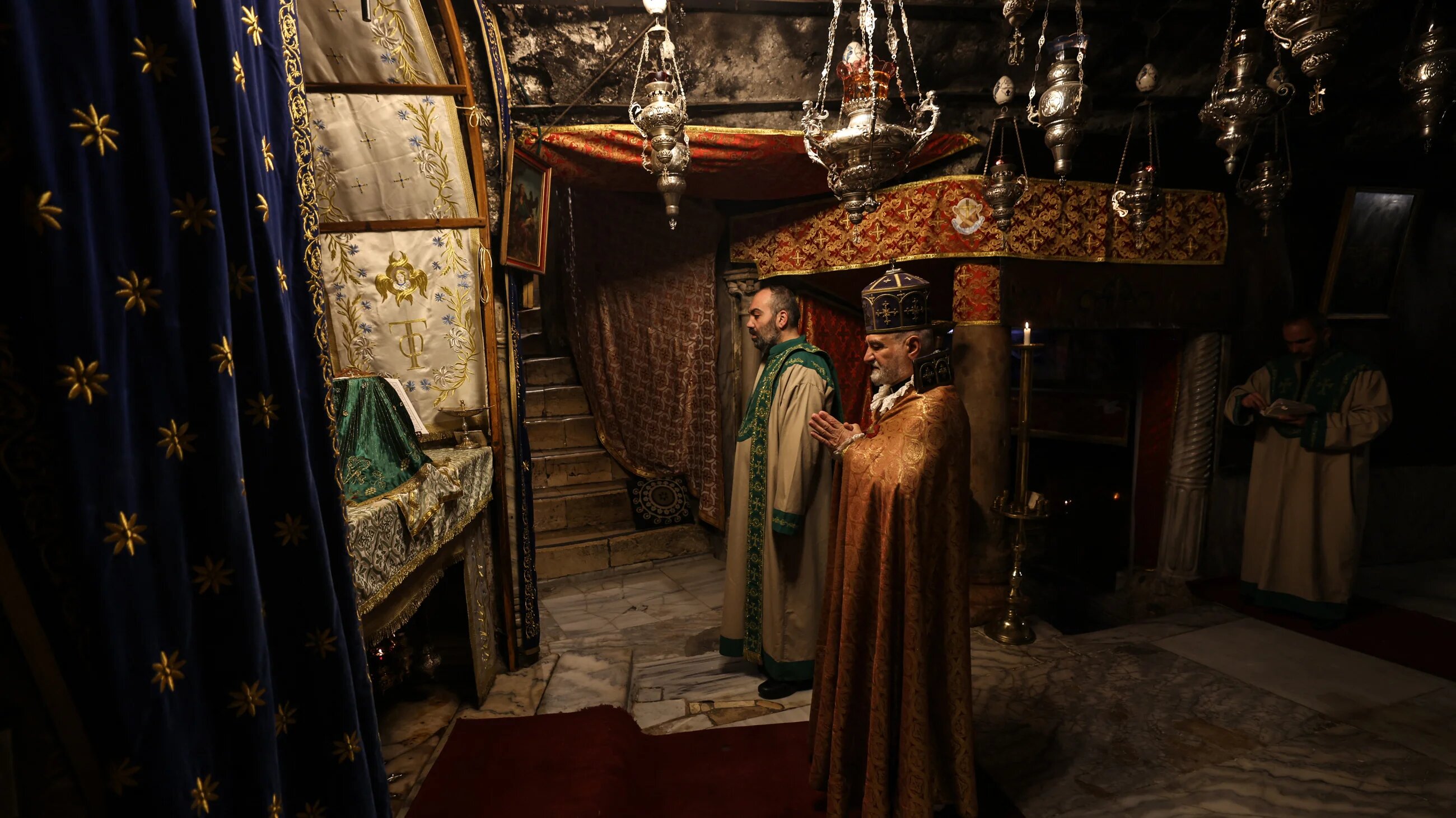 Members of the clergy pray inside the Grotto, believed to be the birthplace of Jesus Christ, in the Church of the Nativity in Bethlehem
