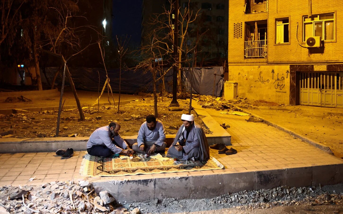 In Iran, Muslims will observe Eid on Saturday. In this photo taken on 18 March 2026, a volunteer team, which helps people clean and restore their homes after US-Israeli air strikes, sits for the iftar meal during Ramadan in Tehran (Majid Asgaripour/WANA via Reuters) 
