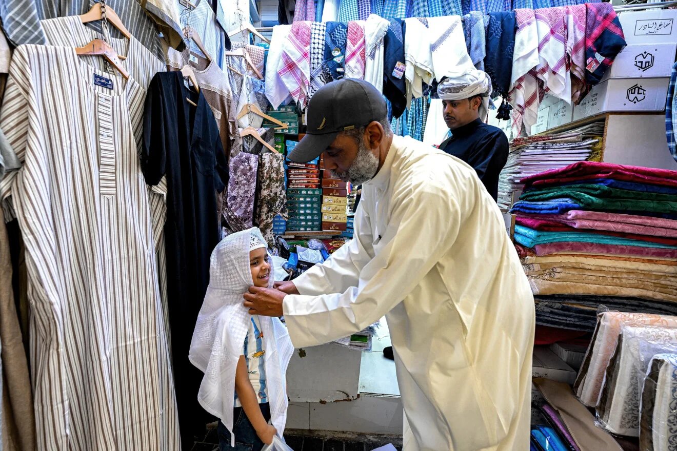 A man helps a boy shop for religious skullcaps while shopping in celebration of Eid al-Fitr at a traditional market in Kuwait City on 19 March 2026 (Yasser al-Zayyat/AFP)