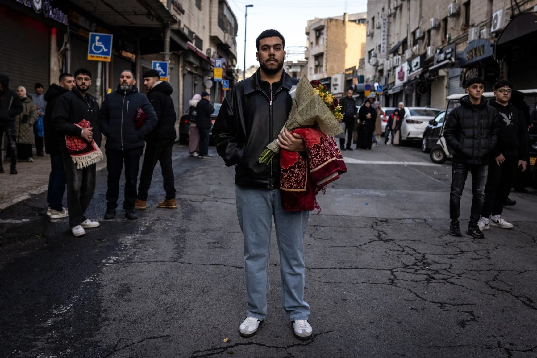 A Muslim worshipper holds a bouquet of flowers and a prayer mat after early morning prayers for Eid al-Fitr along Salah al-Din street in Jerusalem, 20 March 2026 (John Wessels/AFP)