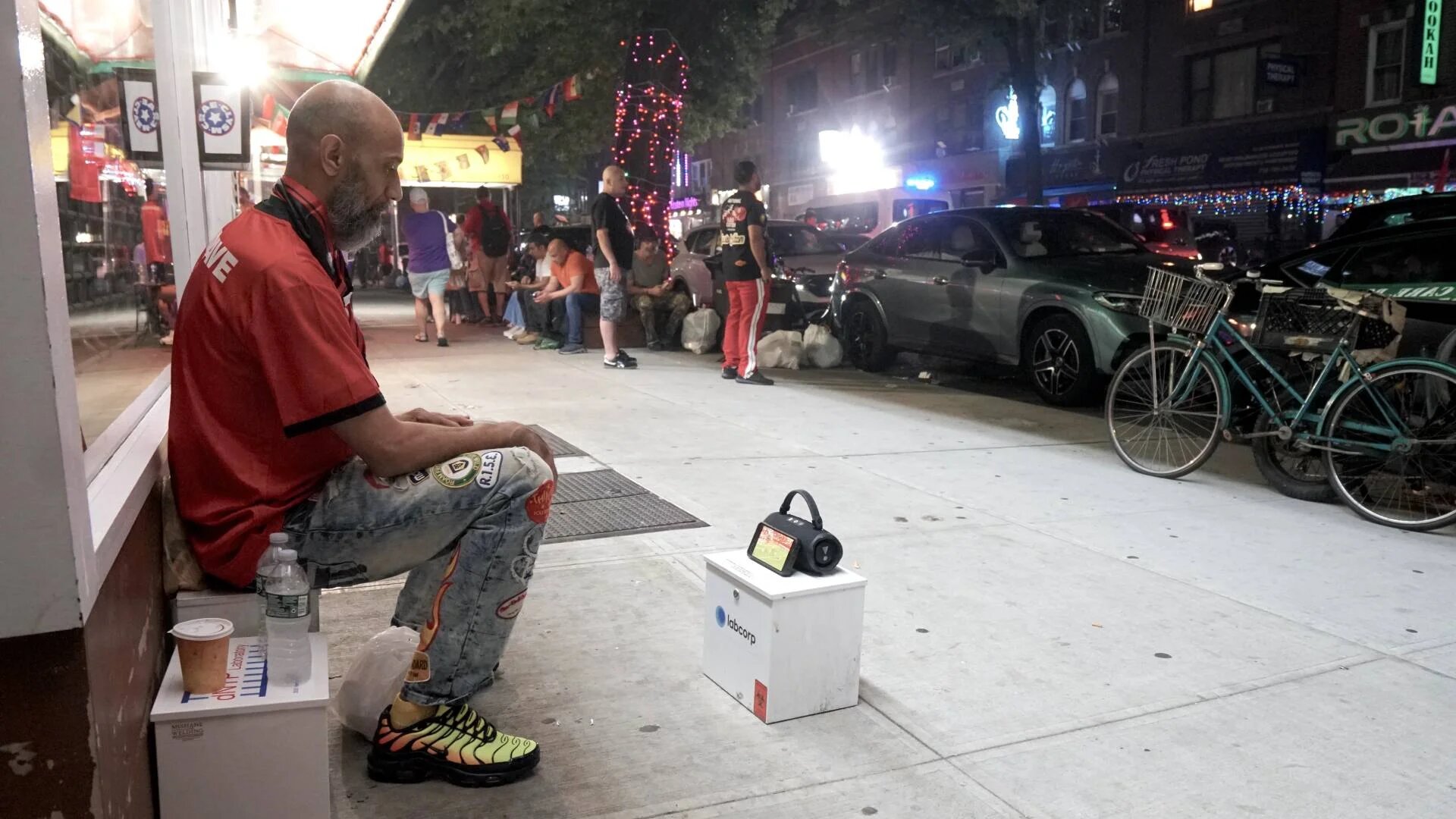 An Egyptian fan watches the World Cup from a custom-built audio-visual setup on a Queens sidewalk (Azad Essa/MEE)