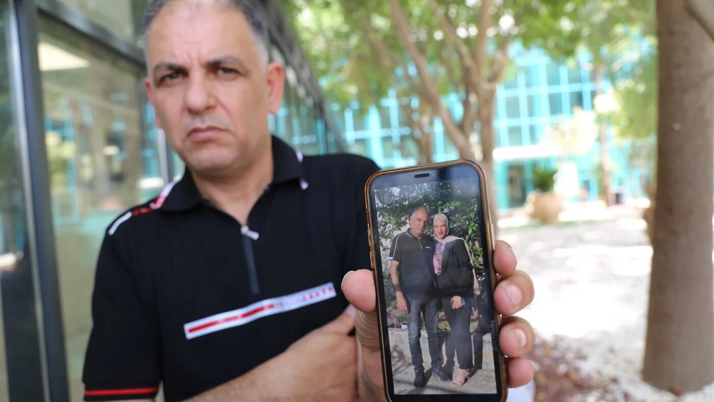 Ghassan Naghniyeh standing outside the Jenin government hospital on Tuesday holding a picture of his 15-year-old daughter Sadeel Naghniyeh (MEE/Leila Warah)