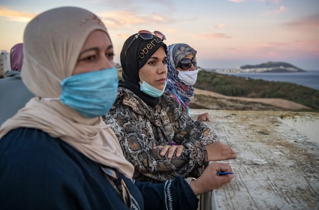 Sur la terrasse d’un immeuble, des employées marocaines de Fnideq regardent vers l’enclave de Ceuta, le 28 août 2020 (AFP)