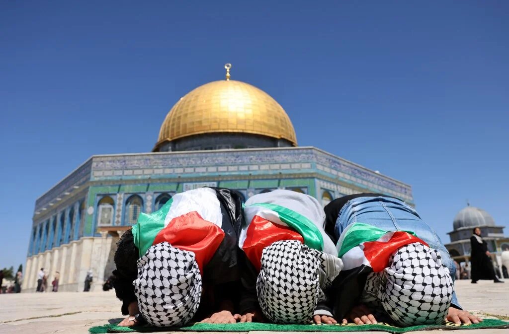  De jeunes Palestiniennes, portant le drapeau national et le keffieh, prient devant le dôme du Rocher à la mosquée al-Aqsa dans la vieille ville de Jérusalem (AFP)