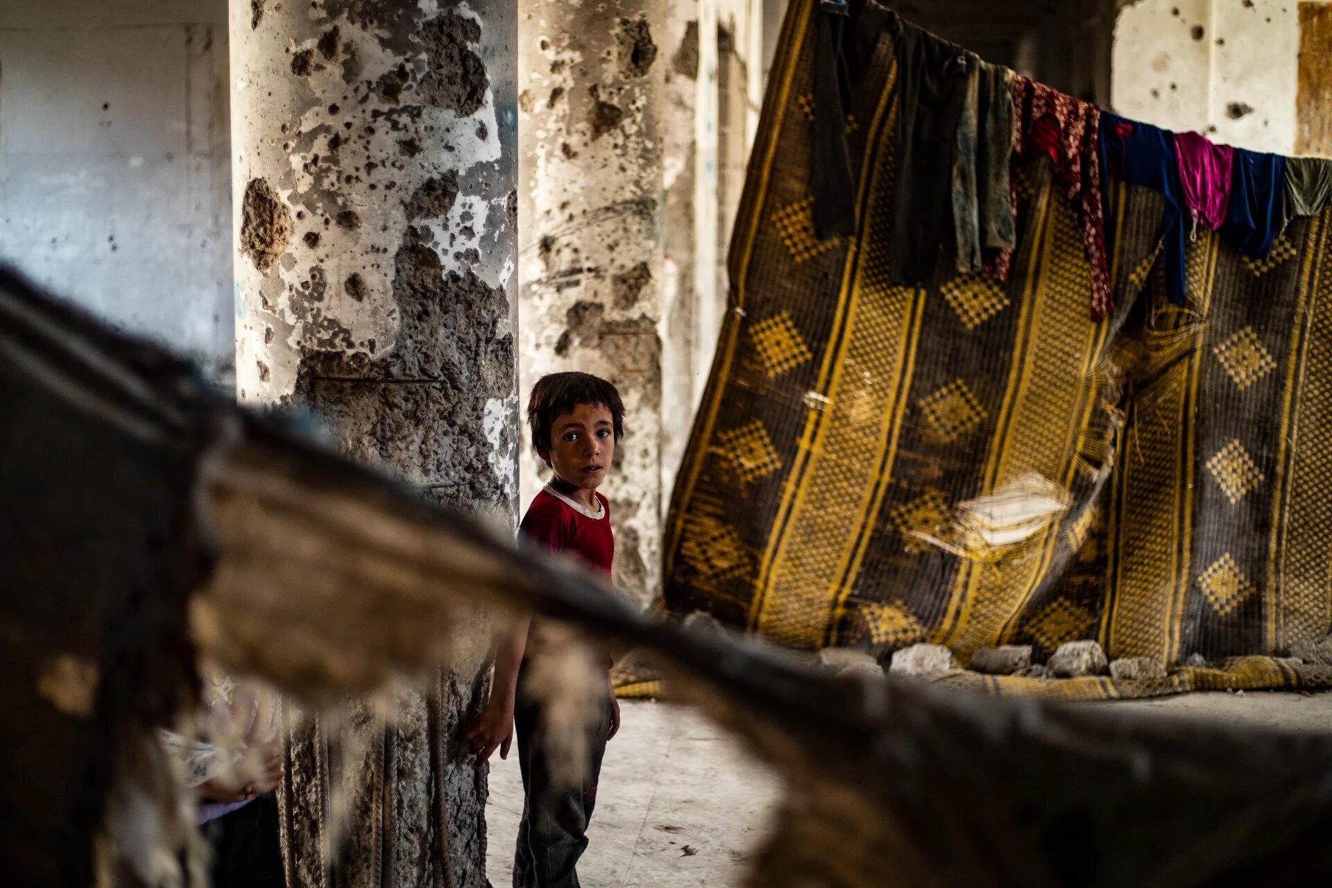 A Syrian boy, displaced with his family from Deir Ezzor, inside the damaged building where she is living in Syria's northern city of Raqqa (AFP)