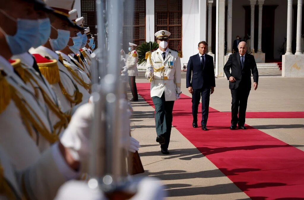 Le président français Emmanuel Macron marche avec le président algérien Abdelmadjid Tebboune, à l’aéroport d’Alger le 27 août 2022 (AFP/Ludovic Marin)