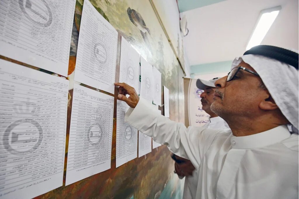 Kuwaiti men check voting lists at a polling station during parliamentary elections in Kuwait City on 29 September 2022 (AFP)