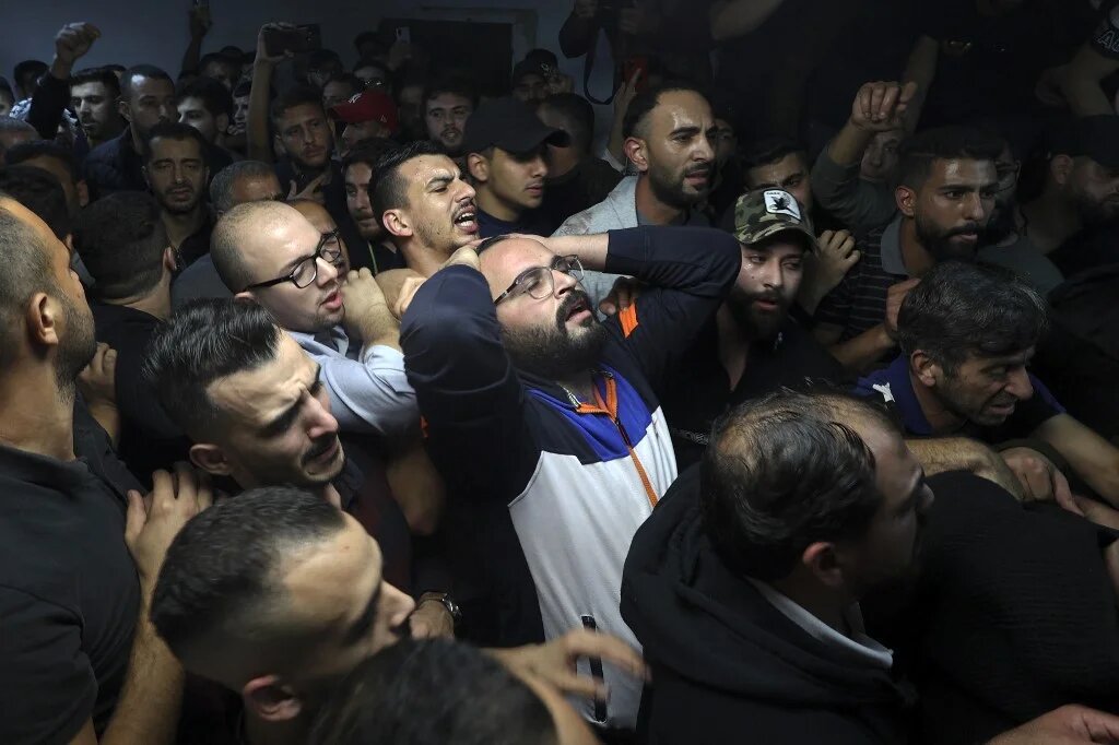 Men mourn near a body of Palestinian at a morgue after Israeli raid in Nablus, in the occupied West Bank on early 25 October 2022 (AFP)