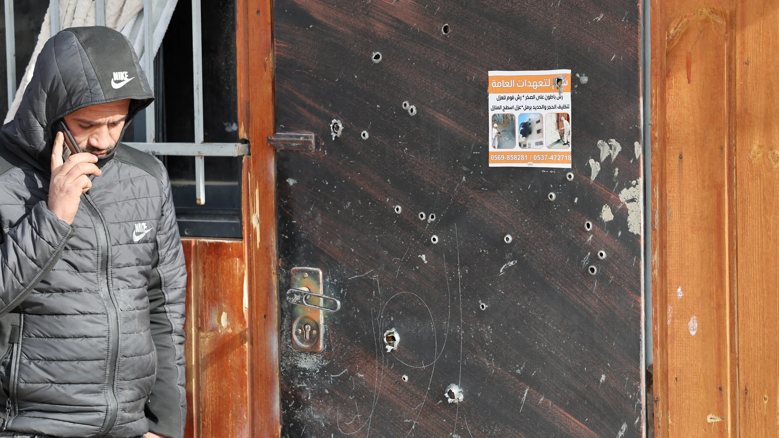 A Palestinian man on his phone at the scene of the Israeli raid on an office where they said Palestinian fighters were hiding in Jericho in the occupied West Bank on 6 February 2023 (AFP)