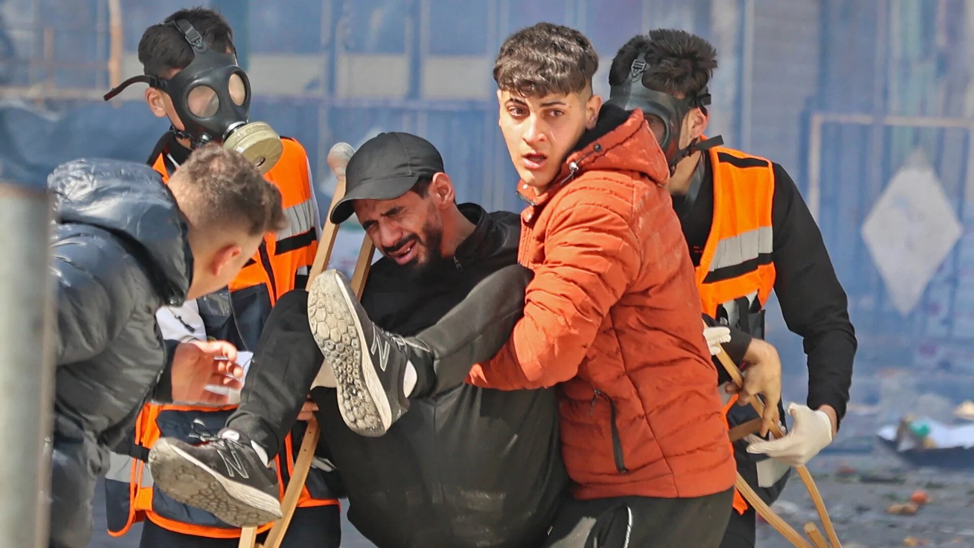 Palestinians carry away a wounded man during an Israeli raid in the occupied West Bank city of Nablus, 22 February (AFP)