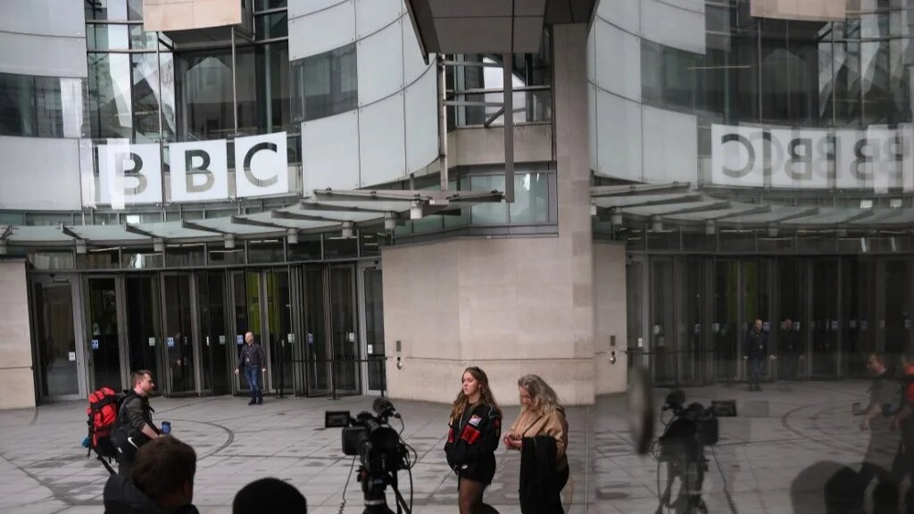 People use the front entrance of the headquarters of the British Broadcasting Corporation (BBC) in London on April 28, 2023