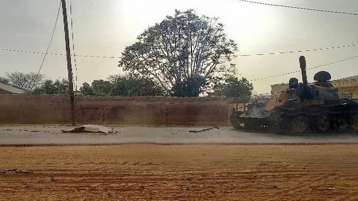 A covered body across from a tank on a street in the West Darfur state capital el-Geneina, on 16 June (AFP)