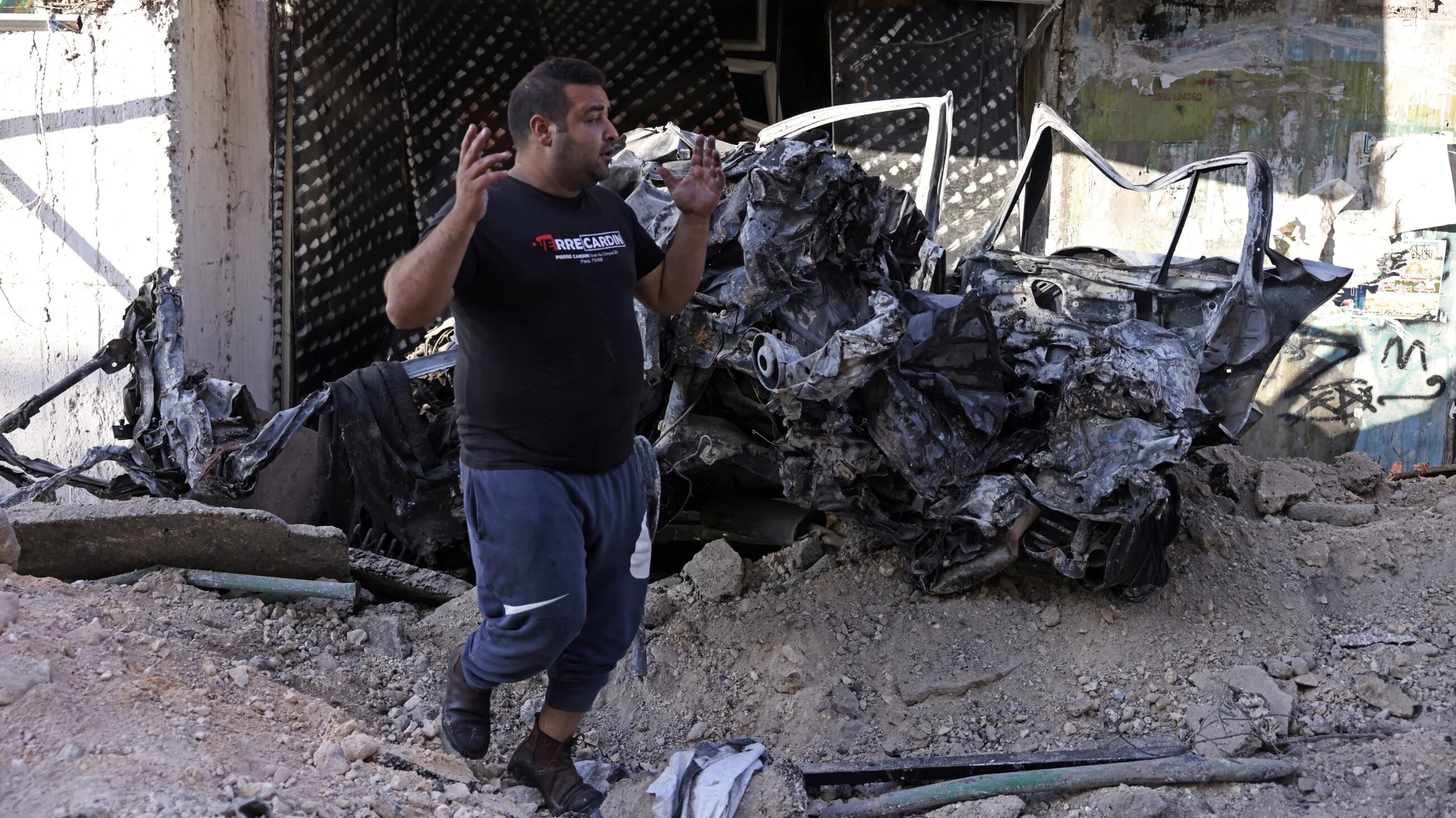 A man walks past a wrecked car in the Jenin refugee camp, occupied West Bank, on 4 July 2023, in the aftermath of an Israeli military operation (AFP)