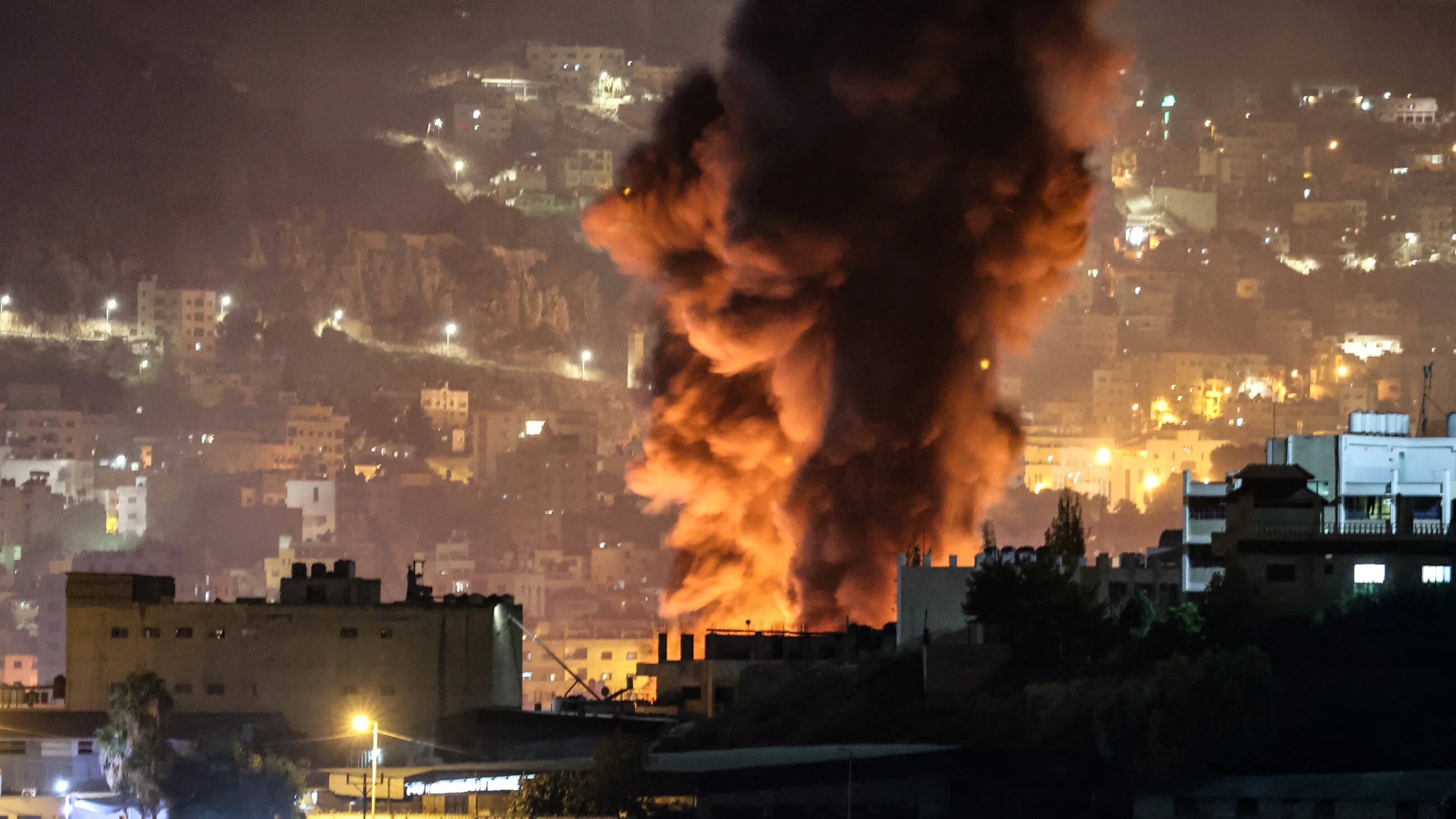 Smoke rises from burning tyres in the eastern area of the occupied West Bank city of Nablus, during an Israeli army raid into the city late on 4 October 2023 (AFP)