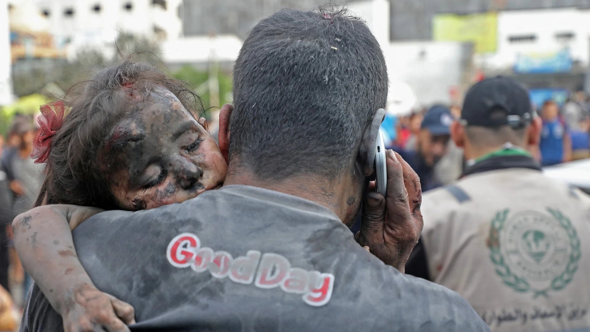 A Palestinian man covered with dust carries an injured baby girl into the Al-Shifa hopsital in Gaza City following Israeli strikes on 29 October (AFP)