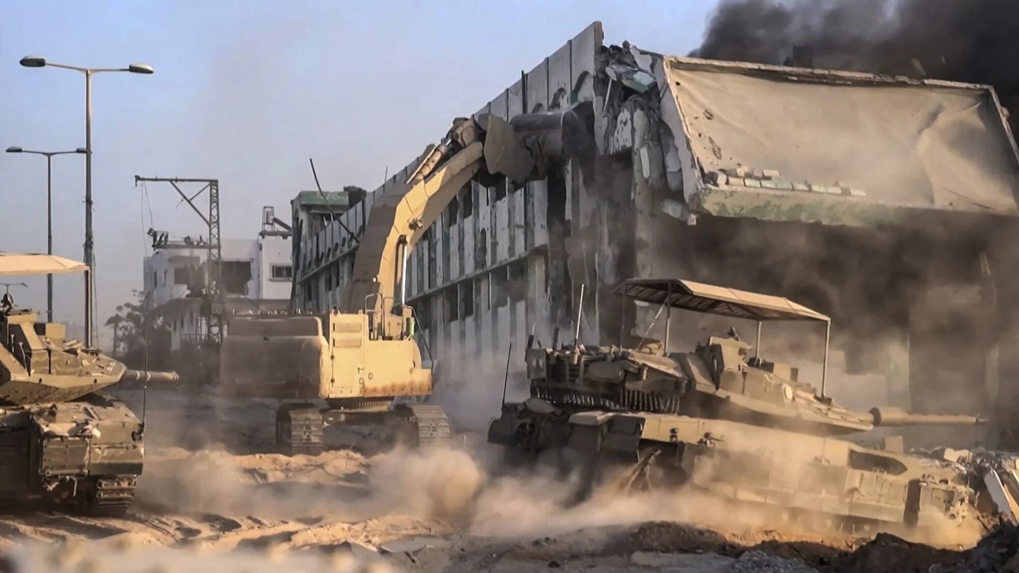 Israeli army tanks and bulldozers demolish a burning building in Gaza in footage released on 11 November 2023 (Israeli army via AFP)