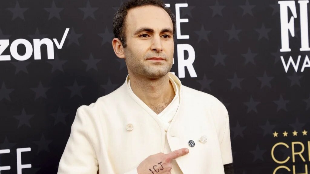 British actor Khalid Abdalla points to pins on his jacket with the letters "ICJ" written on his hand as he arrives for the 29th Annual Critics Choice Awards at the Barker Hangar in Santa Monica, California on January 14, 2024.