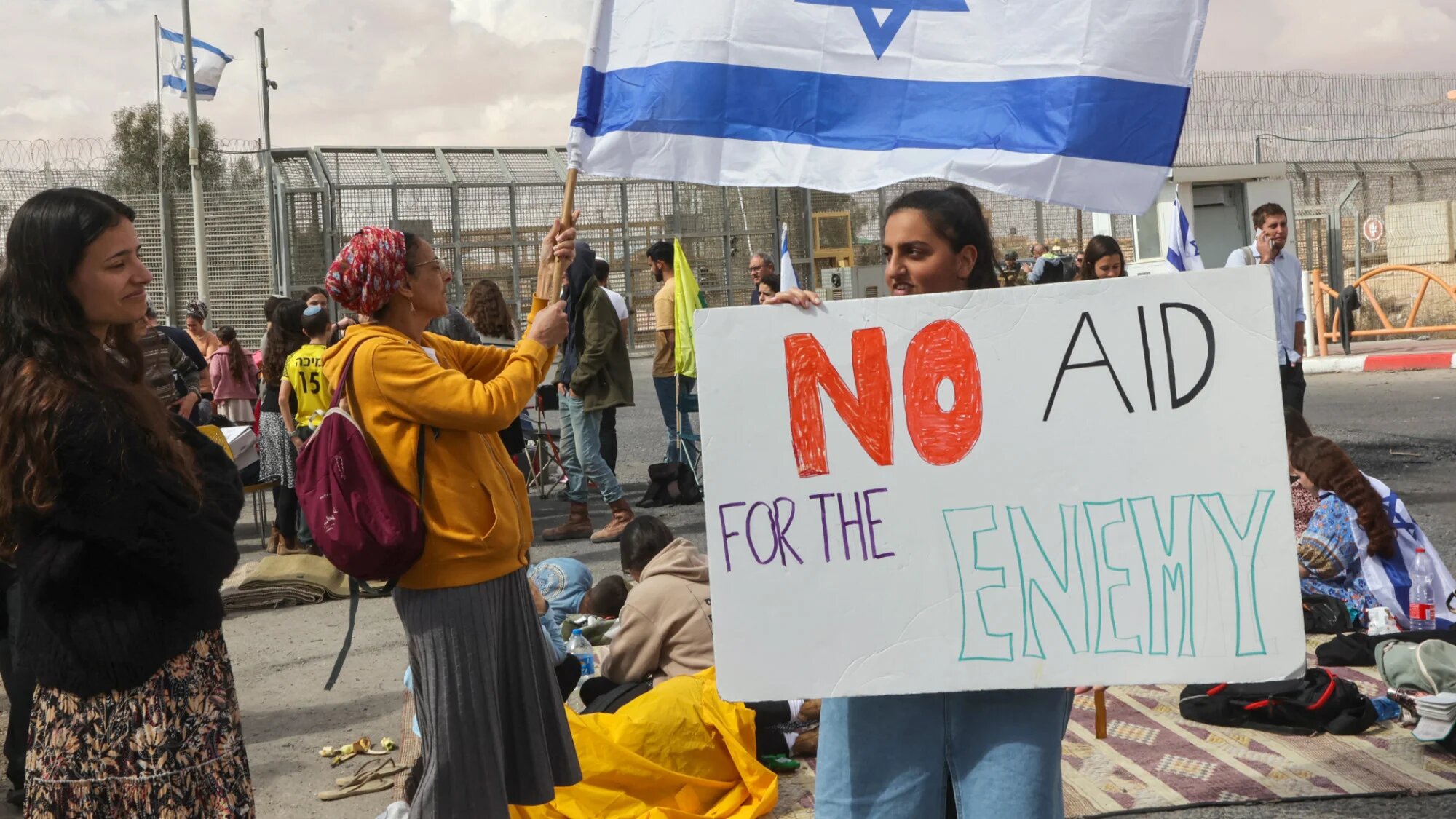 Israeli demonstrators gather by the border fence with Egypt at the Nitzana border crossing in southern Israel on 18 February 2024, as they attempt to block humanitarian aid trucks from entering into Israel on their way to the Gaza Strip (AFP/Gil Cohen-Magen)