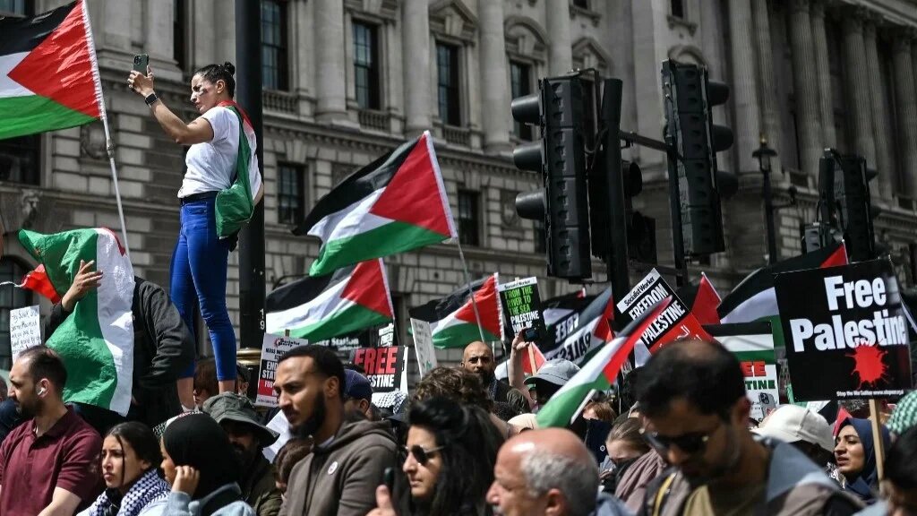 Protesters hold placards and wave Palestinian flags as they gather in Parliament Square, central London, on June 8, 2024 at the end of "National March for Gaza", calling to "end the genocide" and "stop arming Israel" (AFP)