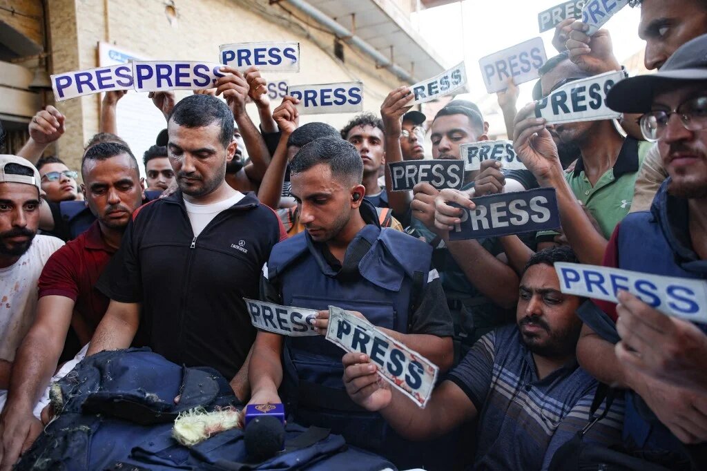 Mourners and colleagues holding 'press' signs surround the body of Al-Jazeera Arabic journalist Ismail al-Ghoul, killed along with his cameraman Rami al-Refee in an Israeli strike in Gaza, on July 31, 2024. (AFP)