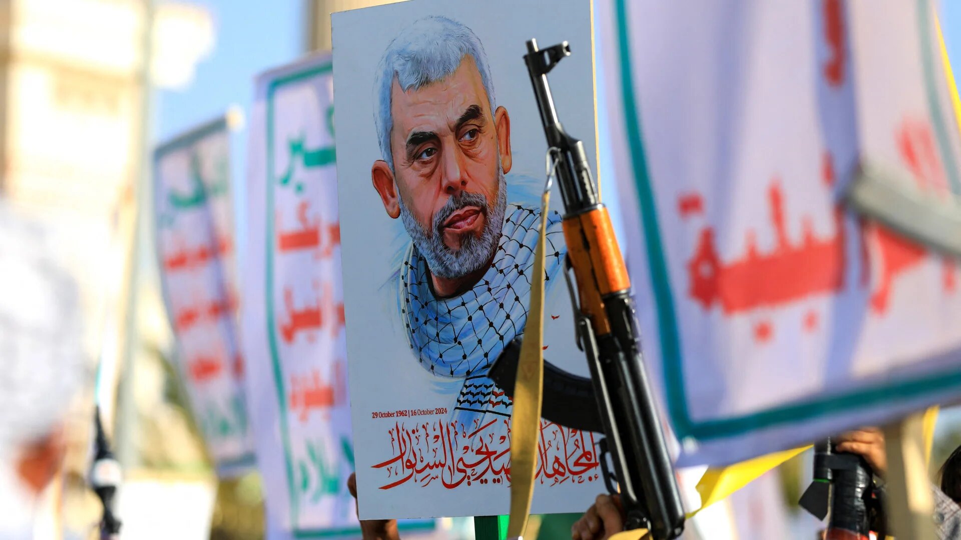 Yemenis brandish rifles and hold a picture of slain Hamas leader Yahya Sinwar during a rally in solidarity with Gaza in Sanaa on 29 November 2024 (Mohammed Huwais/AFP)