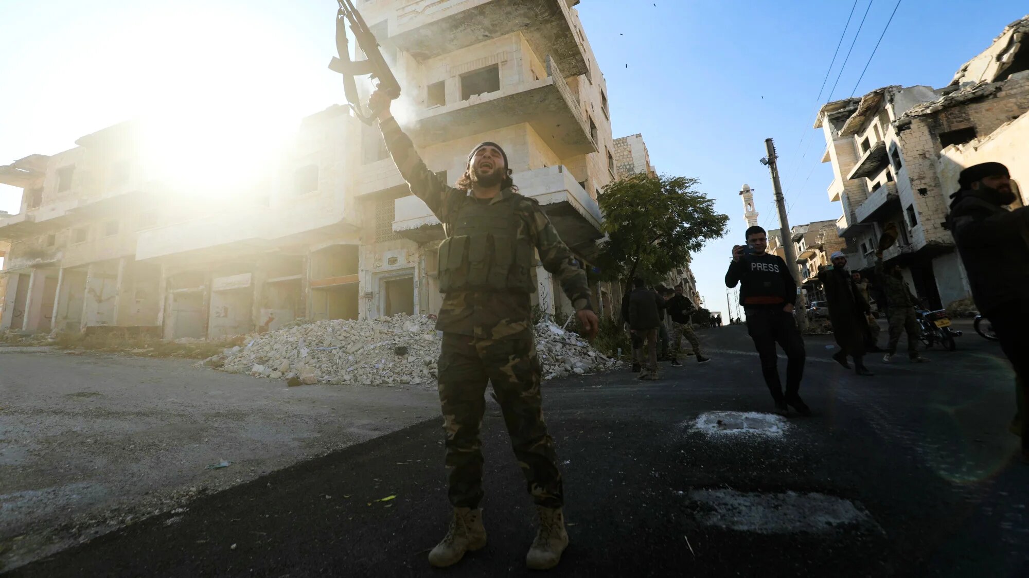 Anti-government fighters celebrate in a street in Maaret al-Numan in Syria's northwestern Idlib province on 30 November 2024 (AFP/Abdulaziz Ketaz)